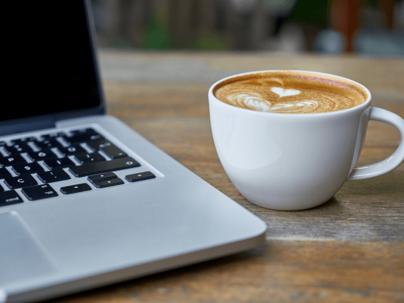 A laptop beside a coffee cup, symbolizing productivity and remote work.