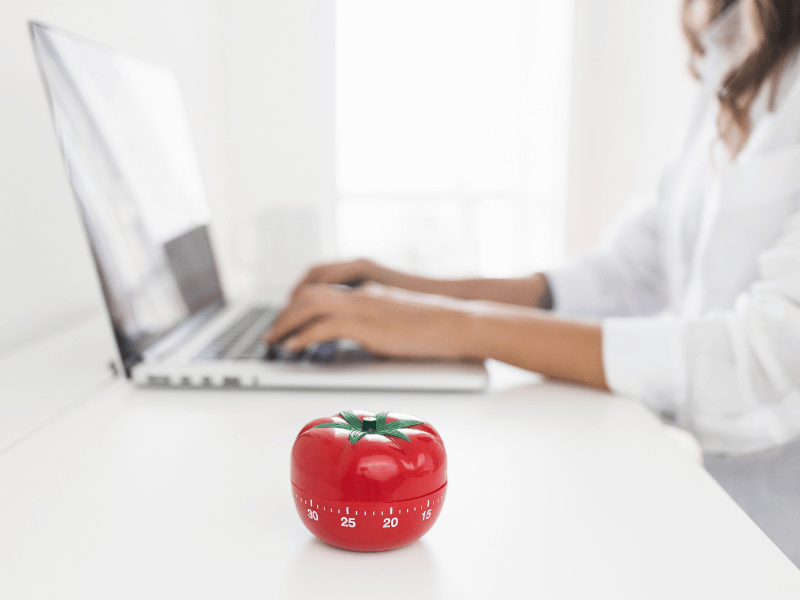 Woman working with a Pomodoro timer on her desk to boost productivity.